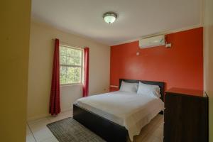 a bedroom with a bed and a red wall at Central 2 bed Apt near Devon House in Kingston +2 photos