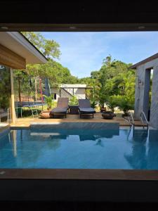 a swimming pool with two chairs and a table at Golden Villa in Ko Phangan
