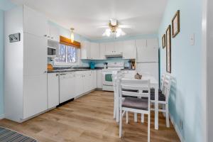 a kitchen with white cabinets and a table and chairs at "At the Eau" - Charming 2 Bedroom Cottage! in Erieau +15 photos