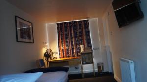 a bedroom with a bed and a window with curtains at YMCA Hotel in London
