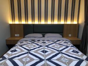 a bedroom with a bed with a blue and white quilt at Apartment Bintaro Icon in Jurangmanggu