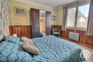 a bedroom with a bed with a blue comforter at Les papillons in Plérin