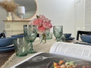 a table with glasses and plates and a book at Tamara Cottage Historic Warmth in Hobart