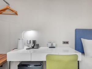 a white desk with a phone and a green chair at CHECK inn Taipei Xinyi in Taipei +150 photos
