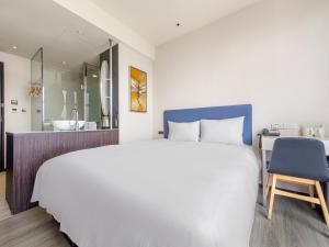 a bedroom with a large white bed and a blue chair at CHECK inn Taipei Xinyi in Taipei