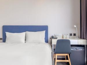 a bedroom with a bed and a desk and a chair at CHECK inn Taipei Xinyi in Taipei