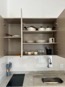 a kitchen with a sink and shelves with dishes at Apartamento 2 Quartos centro da cidade in Parauapebas