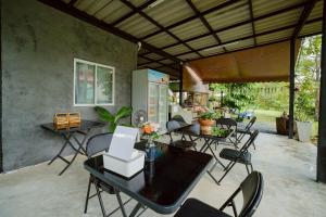 a patio with tables and chairs and a kitchen at Baanklongkok in Ban Map Khangkhao