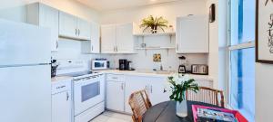 a kitchen with white cabinets and a table with chairs at Sand Star in Russel Island