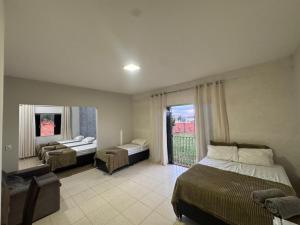 a bedroom with two beds and a large window at Alvorada Hospedagem in Jataí