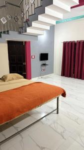 a bedroom with a bed and a tv and stairs at Vanasiri stay inn in Sringeri