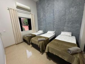 a room with three beds and a window at Alvorada Hospedagem in Jataí