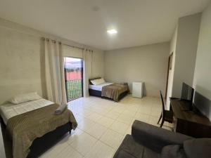 a hotel room with two beds and a couch at Alvorada Hospedagem in Jataí