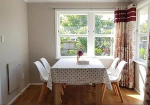 a dining room with a table and white chairs at Stylish Trentham Retreat in Upper Hutt