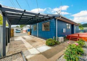 a blue house with a patio and a table at Stylish Trentham Retreat in Upper Hutt