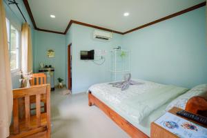 a bedroom with a bed and a desk and a television at Baanklongkok in Ban Map Khangkhao