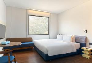a bedroom with a bed and a table and a window at Go Hotel Khon Kaen Campas in Ban Nong Waeng