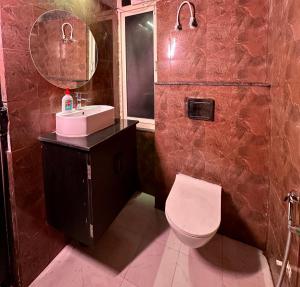 a bathroom with a toilet and a sink and a mirror at Quiet Corner 4BHK Villa in Lucknow