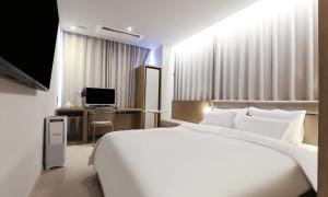 a bedroom with a large white bed and a desk at Wonju Brown Dot Hotel Corporate city in Wonju