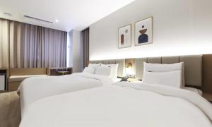 two large white beds in a hotel room at Wonju Brown Dot Hotel Corporate city in Wonju