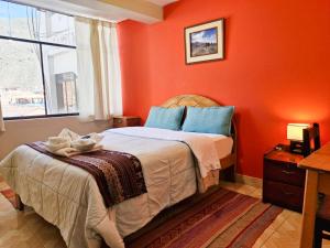 a bedroom with orange walls and a bed with blue pillows at Samaykuy Bed and Breakfast in Urubamba