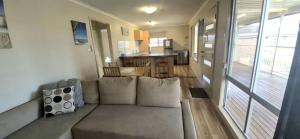 a living room with a couch and a kitchen at Little Sanctuary by Book Jervis Bay - Your Perfect Getaway, A Short Stroll to Palm Beach in Sanctuary Point
