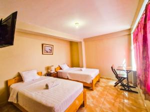 a hotel room with two beds and a flat screen tv at Samaykuy Bed and Breakfast in Urubamba