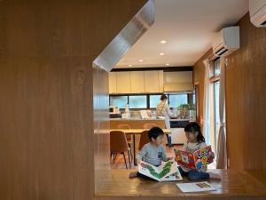 two children sitting on a counter reading books in a kitchen at Yoike Stay in Yonago