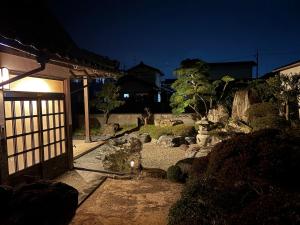 a japanese garden at night with a gate and rocks at Yoike Stay in Yonago
