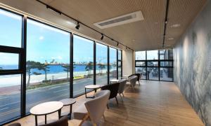 a row of tables and chairs in a room with windows at Pohang Hound Hotel Songdo Beach in Pohang