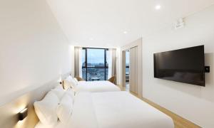 a hotel room with two beds and a flat screen tv at Pohang Hound Hotel Songdo Beach in Pohang