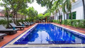 a pool at a hotel with chairs and trees at Harmony Hotel in Siem Reap