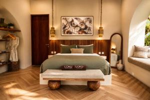 a bedroom with a bed and a bench in it at Loku Kedungu - Boutique Resort in Tanah Lot