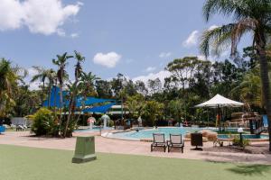 a pool at a resort with chairs and umbrellas at NRMA Ocean Beach Holiday Resort in Umina