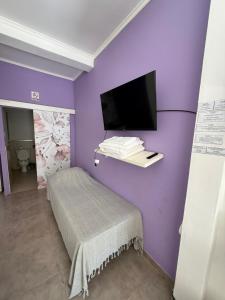 a purple room with a bed and a tv on a wall at Josefina l in Goya
