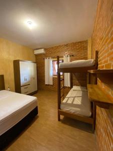 ein Schlafzimmer mit zwei Etagenbetten und einer Ziegelwand in der Unterkunft Cantinho Rústico Brotas SP + Piscina Privativa + Ar Condicionado in Brotas + 31 Fotos