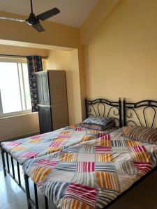 a bedroom with two beds and a refrigerator at SOMNATH Share House in Queula