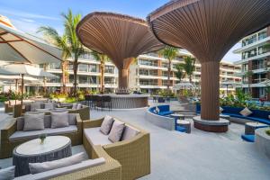 an outdoor patio with tables and chairs and umbrellas at Beachfront Luxury Apartment Bangtao Phuket in Bang Tao Beach