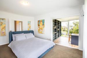 a white bedroom with a bed and a window at Aurora in Queenscliff