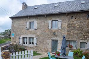 a stone house with a table and chairs in front of it at Gîte de montchamp in Arzenc-dʼApcher