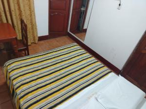 a bed with a yellow and blue striped blanket on it at HOTEL Omar in Ayacucho
