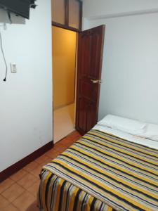 a bedroom with a bed with a striped blanket at HOTEL Omar in Ayacucho