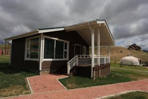 a small house with a porch and a yurt at Red Rock Resort Mongolia in Yoliin Hural