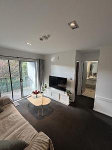 a living room with a couch and a tv and a table at Wānaka Edge Retreat in Wanaka