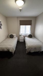 two beds in a room with a window at Wānaka Edge Retreat in Wanaka