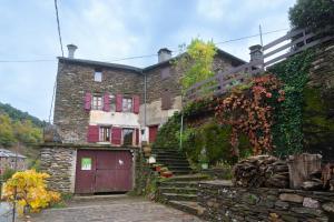 an old stone house with a red door and stairs at Ecogîte cévénola 3 personnes in Molezon