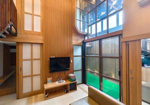 a living room with a tv and large windows at Ohana Suites Yogyakarta in Yogyakarta