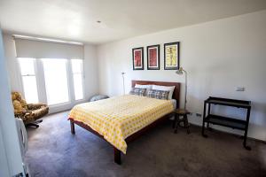 a bedroom with a bed and a chair and windows at Bella Casa in Queenscliff