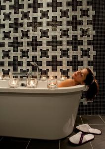 a woman laying in a bath tub in a bathroom at The Fitzwilliam Hotel Belfast in Belfast