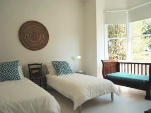 a bedroom with two beds and a bench and a window at Chevignon in Queenscliff